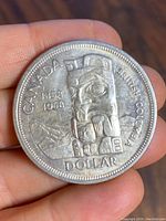 Obverse side of a 1958 Canadian silver dollar coin showing the totem pole and British Columbia centennial design.