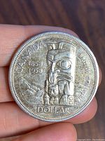 Obverse side of 1958 Canadian silver dollar coin showing totem pole design, dates 1858 1958, and text CANADA DOLLAR BRITISH COLUMBIA