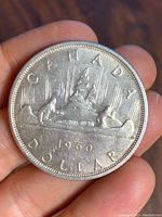 Obverse side of the Canadian 1960 silver dollar coin with Voyageur canoe design.