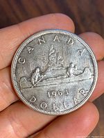 Reverse of the 1963 Canadian silver dollar showing canoe with two paddlers, year 1963, and inscriptions.