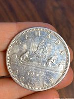 Obverse side of 1965 Canadian silver dollar coin showing voyageur canoe design with 'CANADA DOLLAR' and '1965'.