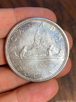 Obverse side of 1966 Canadian silver dollar showing canoe with two figures and date '1966'