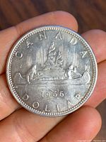 Reverse side of the 1966 Canadian silver dollar coin showing detailed engraving of two figures in a canoe, the year 1966, and the word Canada Dollar.