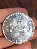 Front side of 1966 Canadian silver dollar coin showing canoe and Northern Lights design with date 1966