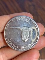 Obverse side of the coin showing flying Canada goose with text 'DOLLAR CANADA 1867-1967'.