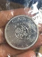 Reverse side of the 1967 Canadian silver dollar coin displaying the floral Centennial design and inscriptions.