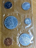 Front side of the 1965 Canadian uncirculated coin set showing silver dollar, half dollar, and other coins sealed in plastic packaging.