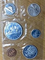 Photo showing front side of the 1966 Canadian uncirculated coins in plastic packaging including 5 cents, 10 cents, 1 dollar, 1 cent, and 50 cents coins