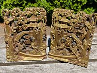 Front and side view of the pair of antique Chinese gilt lacquered wood bookends showing carved scenes with figures, pagodas, trees, boat and bridge details.