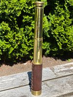 Image of full extended vintage polished brass telescope standing upright showing polished brass and leather wrapping.