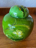Front view of the green glazed antique Chinese porcelain ginger jar highlighting lotus and botanical relief detail on one side.