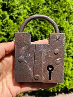 Front view of the rusty iron padlock showing the keyhole and hand forged texture