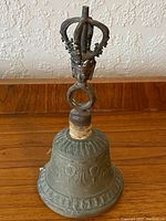 Full view of the bronze bell showing handle and engraved design on the bell body.