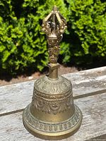 Front and side view of the solid brass Tibetan bell, highlighting the intricate design on the bell's body and the detailed vajra handle.