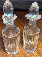 Pair of clear Georgian crystal decanters with octagonal bases and faceted teardrop stoppers. Both have decorative collars at the neck.