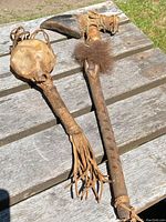 Both Indigenous ceremonial items displayed side by side on a wooden table outside under natural light.