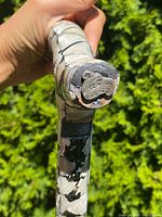 Close-up image of the end of the curved handle showing the detailed silver raven's head plaque and mother of pearl inlay around it.