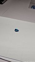 Photo showing deep lagoon blue pear cut topaz gemstone on white background displaying color and cut