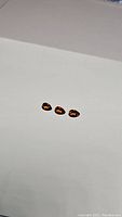 Three pear-shaped natural Spessartite garnet gemstones shown from a slight distance on a white background, illustrating overall size and shape.