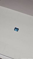 Clear photo showing a single emerald cut Swiss blue topaz gemstone on a plain white background.