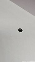 Oval green sapphire gemstone on white background showing facets and color.