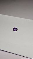 Oval cut natural Bolivian amethyst gemstone placed on white background showing deep purple color and polished facets.