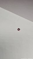Bright pink spinel gemstone shown on a white background, showcasing its color and clarity.