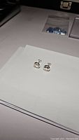 Pair of clear faceted quartz earrings set in sterling silver, displayed on white paper.