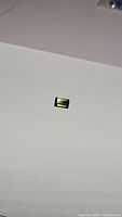 Single bright green rectangular baguette cut tourmaline gemstone on a white background, showing the facets and color clearly.