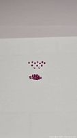 Top view of multiple small square cut rubies arranged in two groups against a white background.