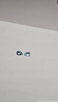 Pair of pear-shaped sky blue topaz gemstones, approx 7x5mm, showing color and clarity from one angle.