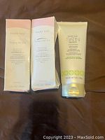 Three Mary Kay skincare products: two boxed Timewise Age-Fighting Moisturizers with sunscreen SPF 15 and one Satin Body Lotion tube on brown fabric.