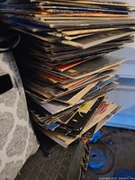 Side view of a large stack of 40 vinyl record albums showing many album covers with varying wear.