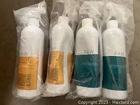 Four sealed Paw Sense cleaning product bottles, 2 with orange stain & odor remover labels and 2 with teal shampoo labels, all white plastic bottles with spray or flip caps in plastic wrapping.
