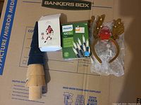 Full view of lot items including fabric Christmas tree, NFL Hall of Fame Matt Hasselbeck ornament box, Philips Christmas lights, and two reindeer antler headbands.