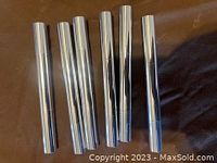 Six silver metallic teeth whitening pens arranged horizontally