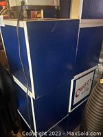 Side view showing three stacked blue and white cubes with white framing and visible minor wear.