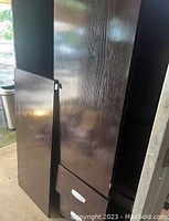 Dark wooden armoire with a door detached and two bottom drawers visible.