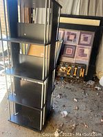 Front view of black multi-shelf tower for media storage, showing multiple shelves and silver metal supports.