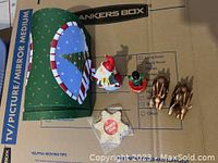 Photo showing all items including the green mailbox gift box, Santa, nutcracker on drum, two reindeer, and packaged star-shaped ornament, all arranged on moving boxes.