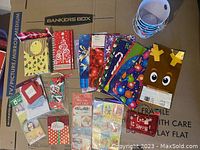 Top down image showing an assortment of holiday-themed gift bags, gift tag sticker packs, treat bags, and small buckets.