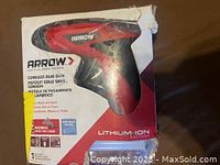 Photo of Arrow cordless glue gun in damaged packaging showing red and black gun and branding.