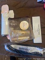 Front view of the Mary Kay set items including some products in mesh bag, aromatherapy box, and hair band on brown surface.