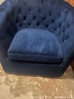 Front view of cobalt blue velvet barrel back swivel armchair with tufted back.