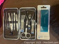 Open metal manicure kit showing various stainless steel nail tools including clippers, scissors, pushers arranged neatly in elastic bands.