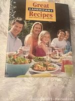 Cover photo of the recipe book titled 'Great American Recipes' featuring a family sitting around a dinner table with food dishes.
