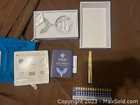 Full kit contents including mouthpiece with cables, whitening pen, lip balm, user manual, teeth shade guide sheet, and blue branded storage pouch, displayed on flat brown surface.