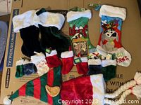 Photo showing assorted Christmas stockings including mini stockings, dog-themed stockings, and regular stockings arranged on cardboard surface.