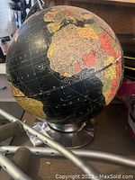 Photo highlighting the globe showing Africa, South America, and surrounding oceans with the metal base visible.