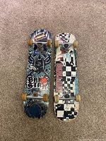 Full top view of two vintage skateboards side-by-side on carpet, showing overall graphics and wear.